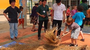 Les gestes du battage du riz dans la cour du lycée de Bangkok.